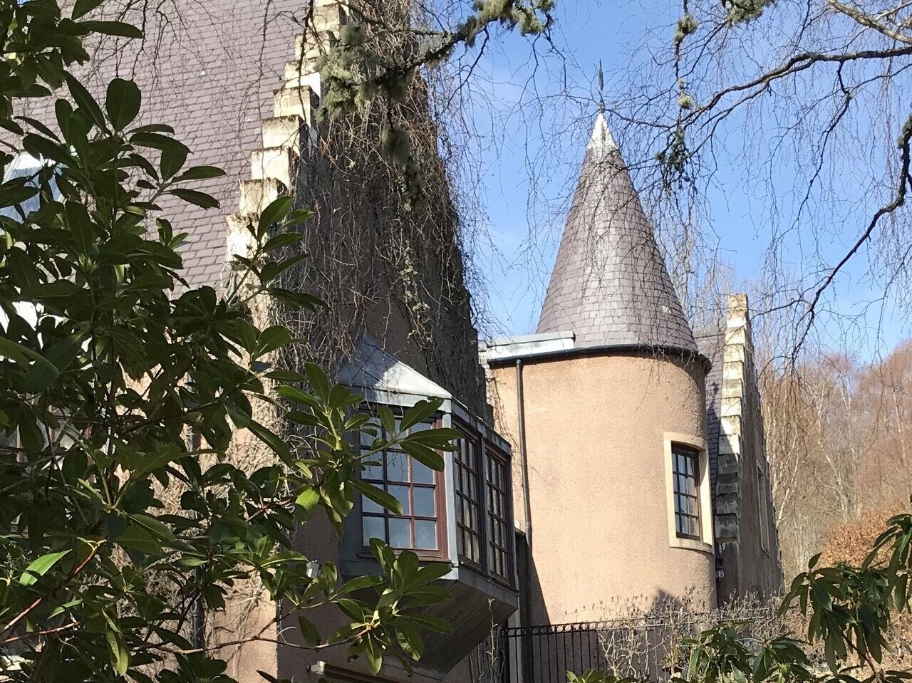 A historic building with a tower, a window with a white frame, and a brick wall.