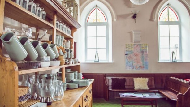 A room with wooden shelves displaying various ceramic items, a wooden bench, and a table with papers. - Kirkby Stephen Hostel (Kirkby Stephen)