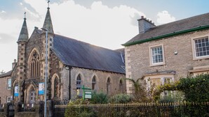 A historic church with twin spires and a stone facade, adjacent to a traditional stone building with a green roof. - Kirkby Stephen Hostel (Kirkby Stephen)