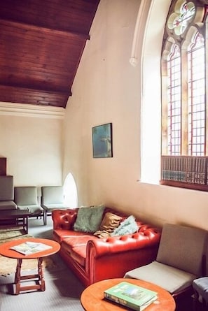 Una habitación acogedora con un sofá de cuero rojo, dos sillones y una mesa de centro de madera.