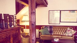 A cozy living room with a leather sofa, a wooden coffee table, and a bookshelf. - Kirkby Stephen Hostel (Kirkby Stephen)
