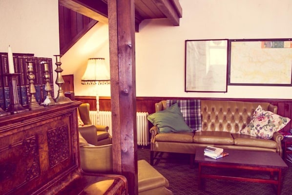 A cozy living room with a leather sofa, a wooden coffee table, and a bookshelf.