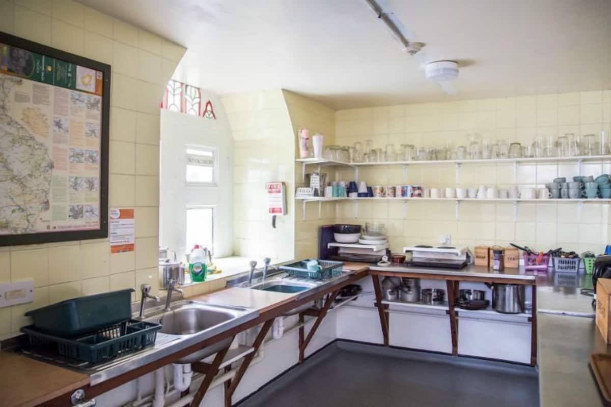 A kitchen with a map on the wall, a sink, and shelves with kitchenware.