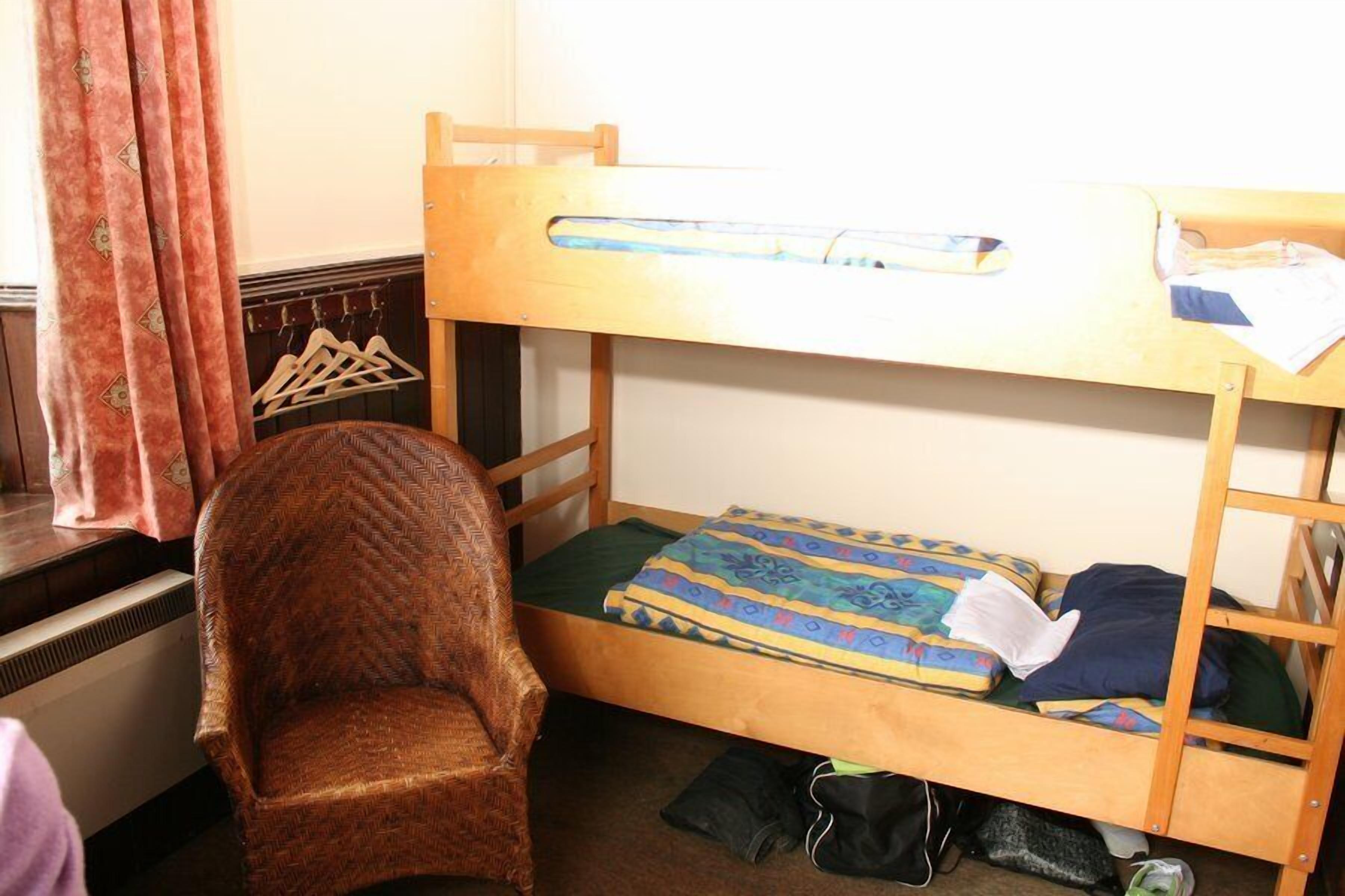 A bunk bed with a wooden frame, a chair, and a radiator.
