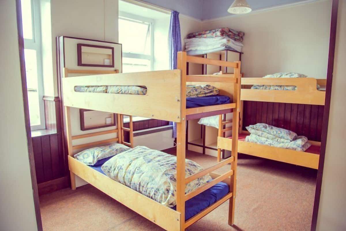 A bunk bed room with a window, a framed picture on the wall, and a ceiling light fixture.