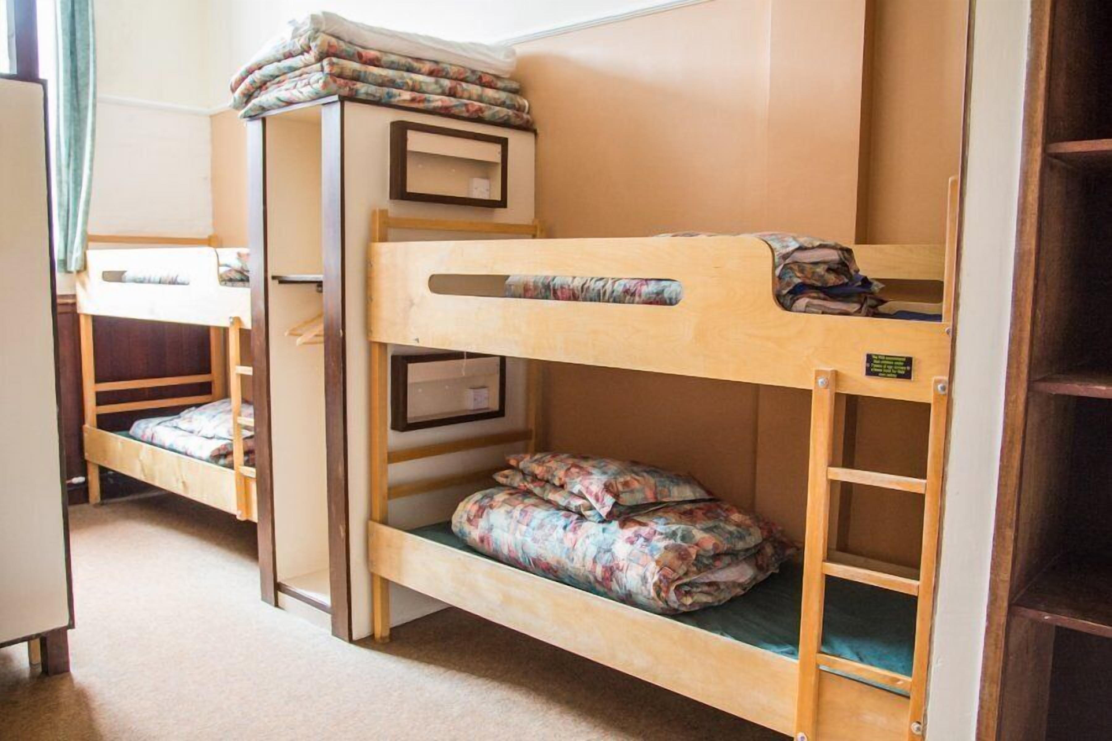 A bunk bed room with a desk and a wardrobe.