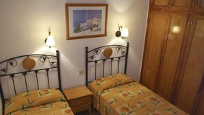 Une chambre avec deux lits, chacun recouvert d’une couvre-lit à motifs floraux, un placard en bois et un tableau encadré au mur.