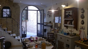 Un comedor con una mesa preparada para cuatro personas, una escalera y vistas al exterior.