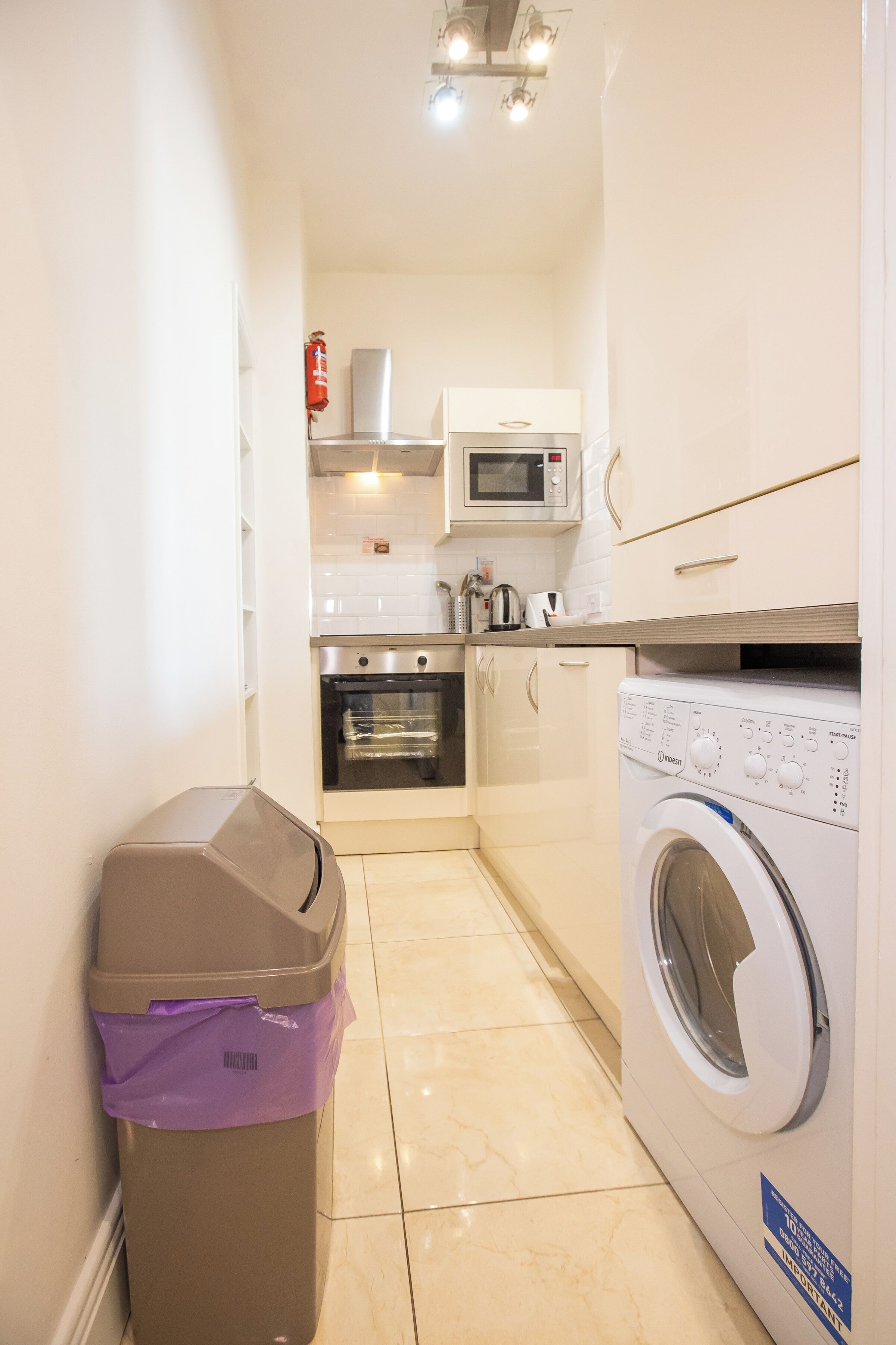 A compact kitchen with a microwave, oven, and washing machine.