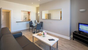 A modern living room with a sofa, a coffee table, and a TV on a stand. - Temple Bar Wellington Quay Apartments (Dublin)