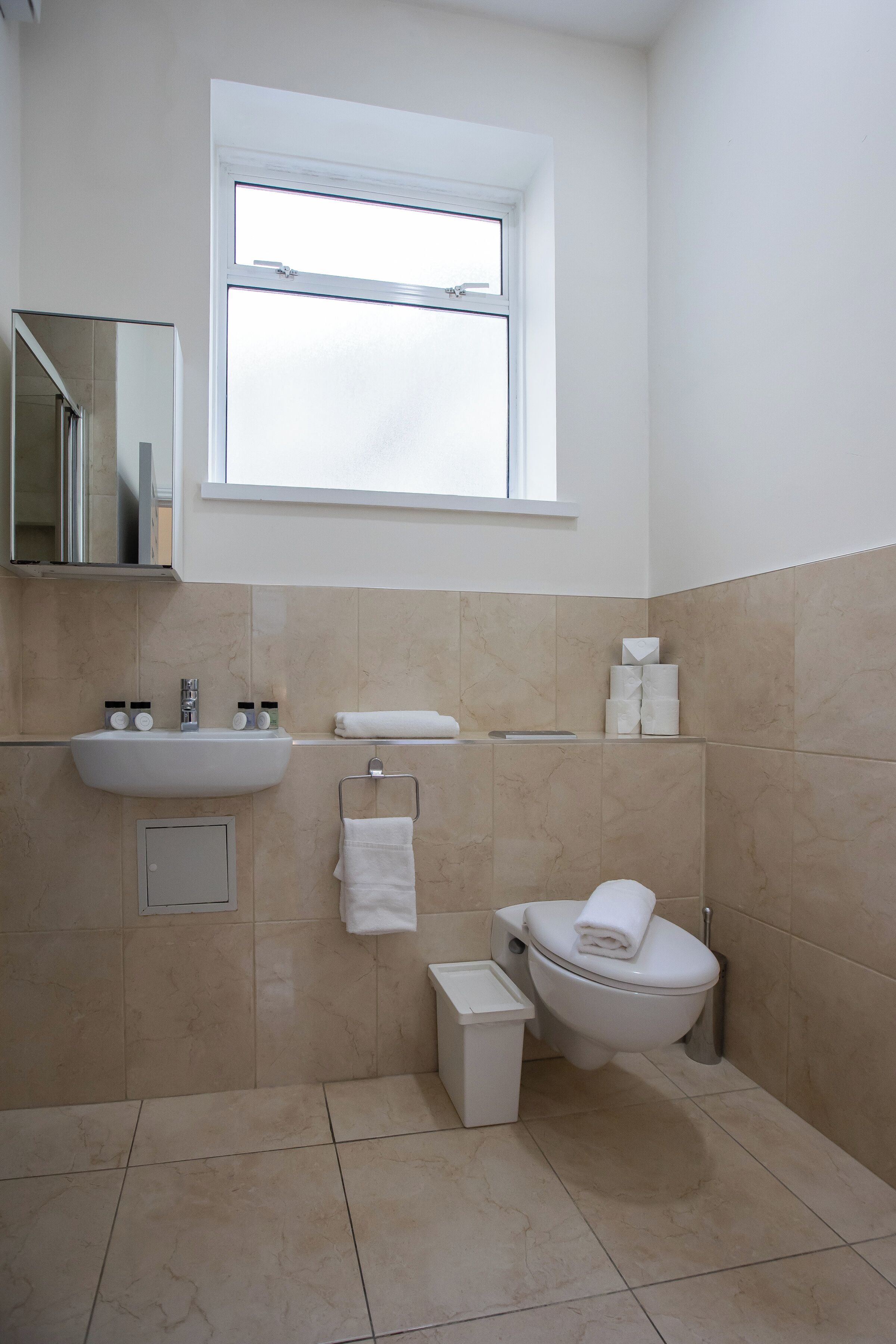 Un baño moderno con lavamanos, inodoro y espejo.