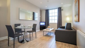 A modern living room with a dining area, a sofa, a coffee table, and a TV. - Temple Bar Wellington Quay Apartments (Dublin)