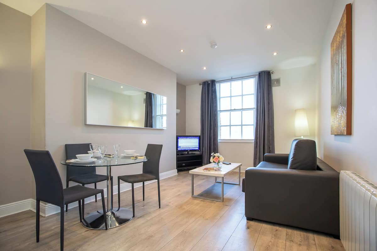 Una sala de estar moderna con comedor, sofá, mesa de centro y televisor.