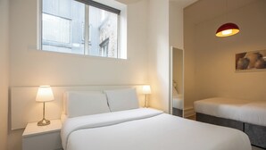 A hotel room with a large bed, two bedside tables with lamps, a window, and a painting on the wall. - Temple Bar Wellington Quay Apartments (Dublin)
