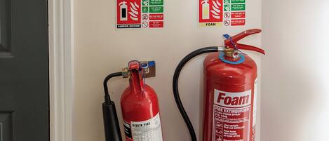Ein an der Wand befestigter Feuerlöscher mit Zughebel und einem roten Schaumlöscher mit den Aufschriften "Foam" und "Commander" darunter.