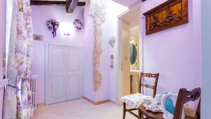 A room with a wooden door, a table with a floral tablecloth, and a chair. - Bed and Breakfast Sognando Te (Assisi)