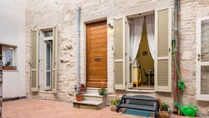 A stone building with a wooden door, a bench, and potted plants outside. - Bed and Breakfast Sognando Te (Assisi)