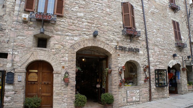 A stone building with a wooden door, potted plants, and a sign that reads "TRE ARCHI". - Bed and Breakfast Sognando Te (Assisi)