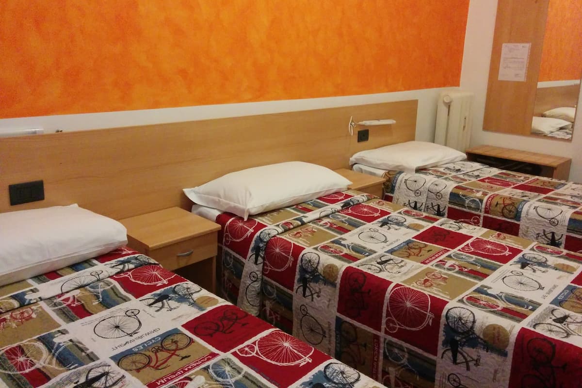 Quarto de hotel com duas camas de solteiro, cada uma com capa de edredom com tema de bicicleta, uma cabeceira de madeira, uma mesa de cabeceira e um espelho.