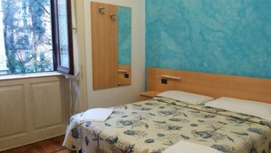 Une chambre à coucher avec un lit, une fenêtre, un miroir et un mur bleu.