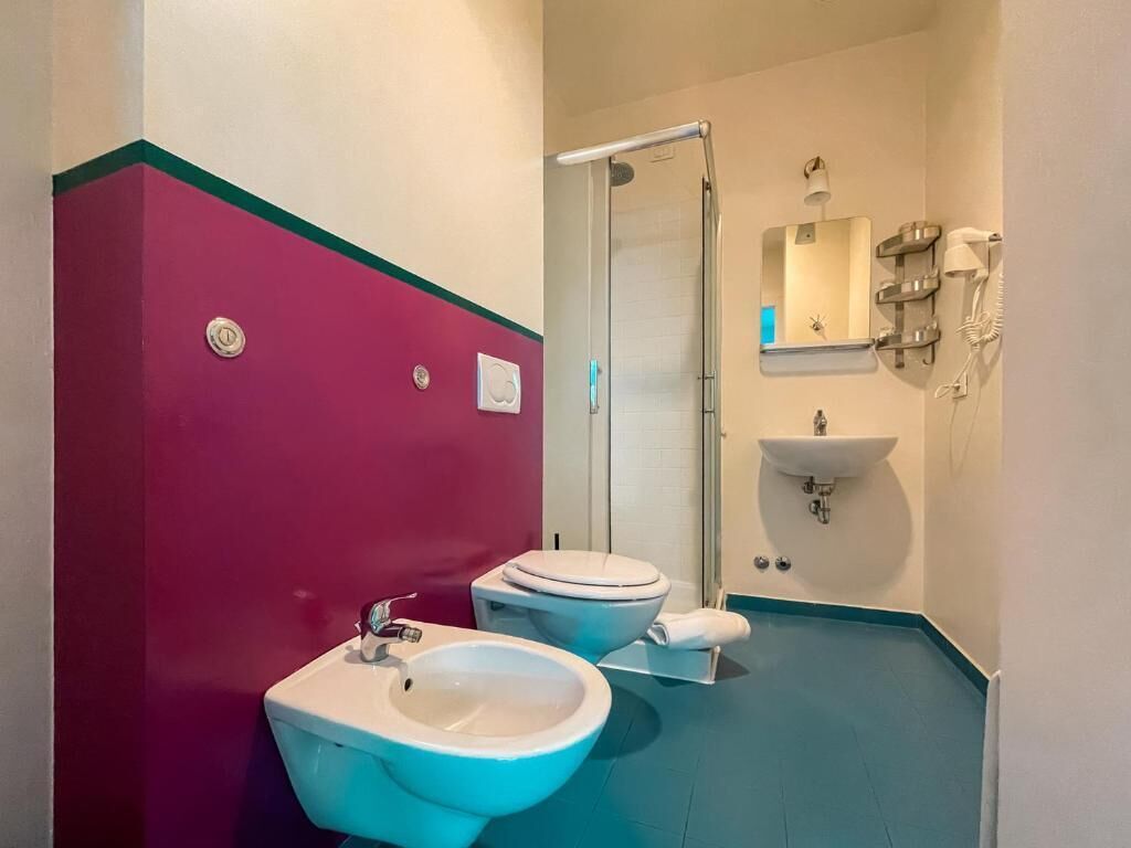Un baño con dos inodoros, un lavabo, una ducha y un espejo.
