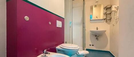 Un baño con dos inodoros, un lavabo, una ducha y un espejo.