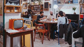 Ein gemütliches Café mit Holzmöbeln, einem alten Fernseher und diversen Dekorationen.