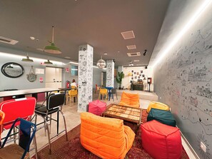 A modern lounge area with colorful seating, a bar, and a wall decorated with drawings. - Ostello Bello Milano Duomo (Milan)