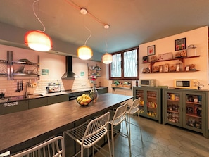 A modern kitchen with a central island, bar stools, a built-in microwave, and a variety of storage cabinets.