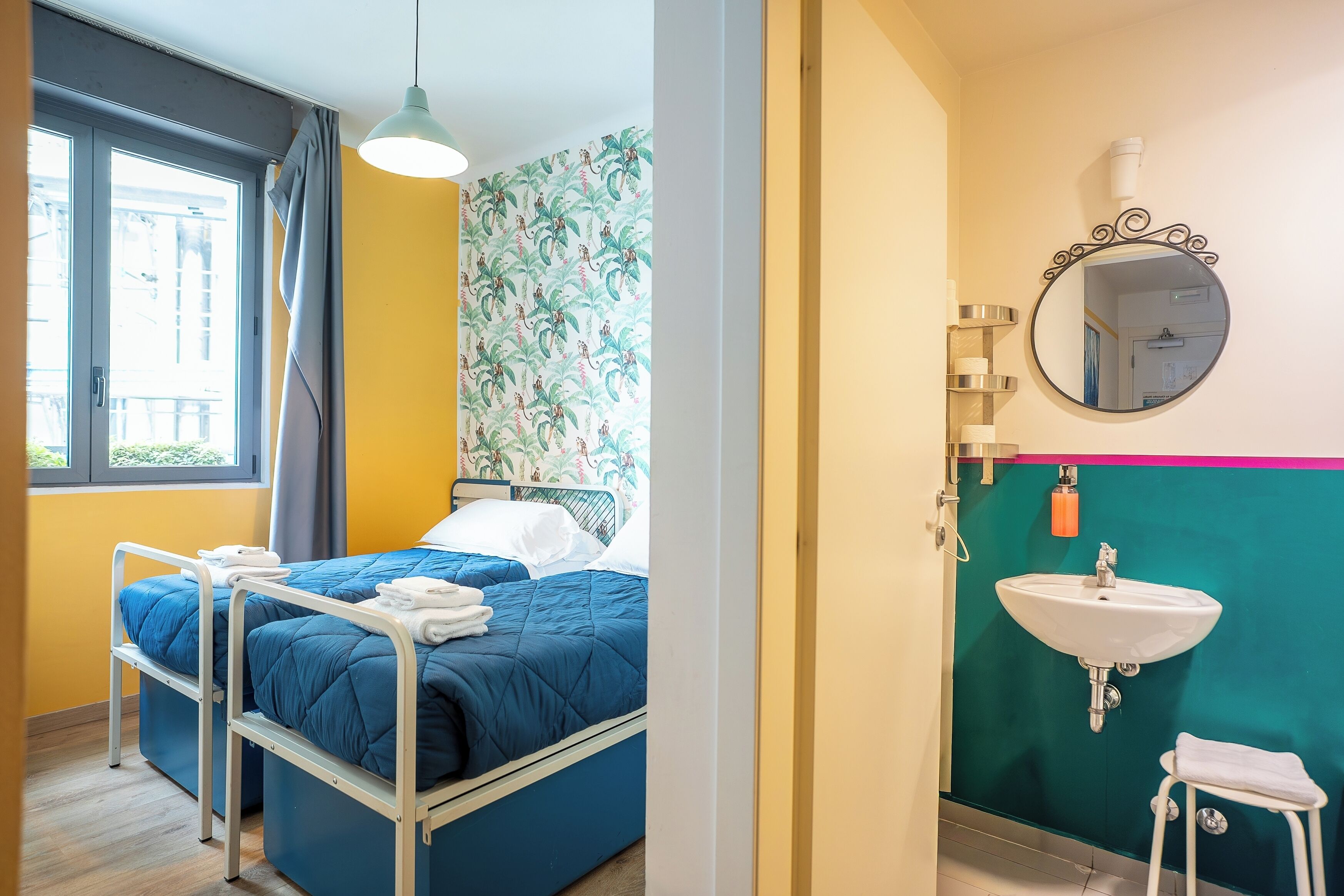 A room with a bed, a window, a sink, and a mirror.