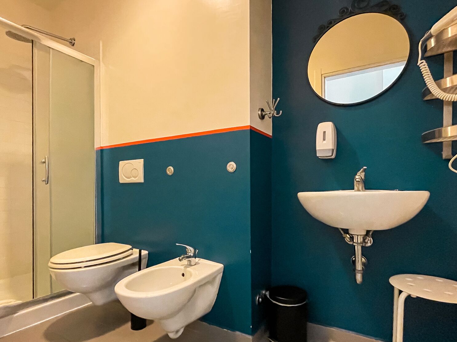 A bathroom with a toilet, bidet, sink, and mirror.
