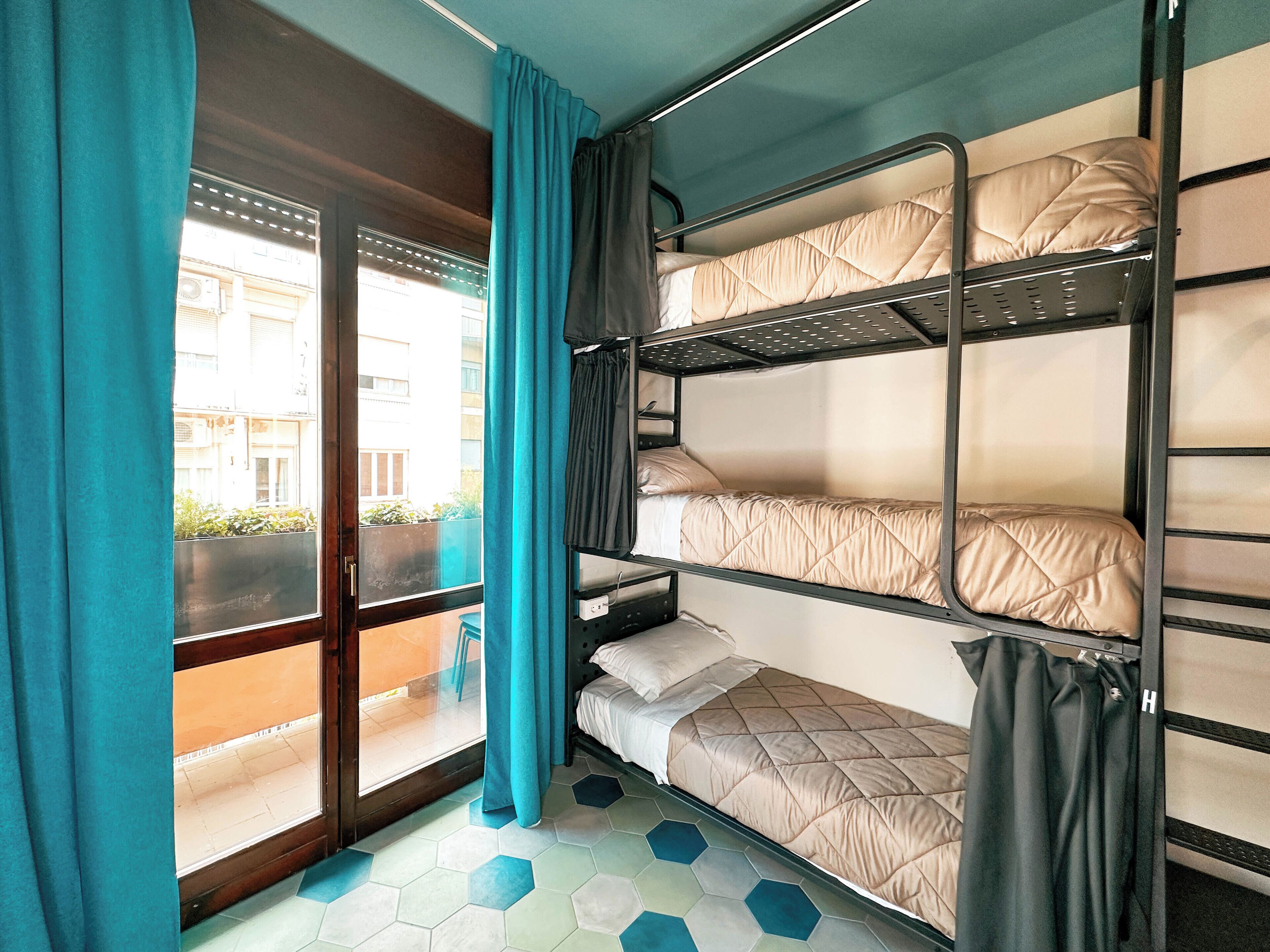Une chambre avec des lits superposés donnant sur les bâtiments environnants.