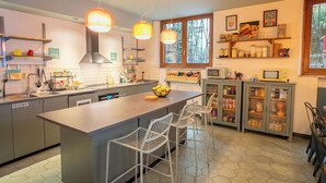 A modern kitchen with a central island, bar stools, a microwave, and a window with a view. - Ostello Bello Milano Duomo (Milan)