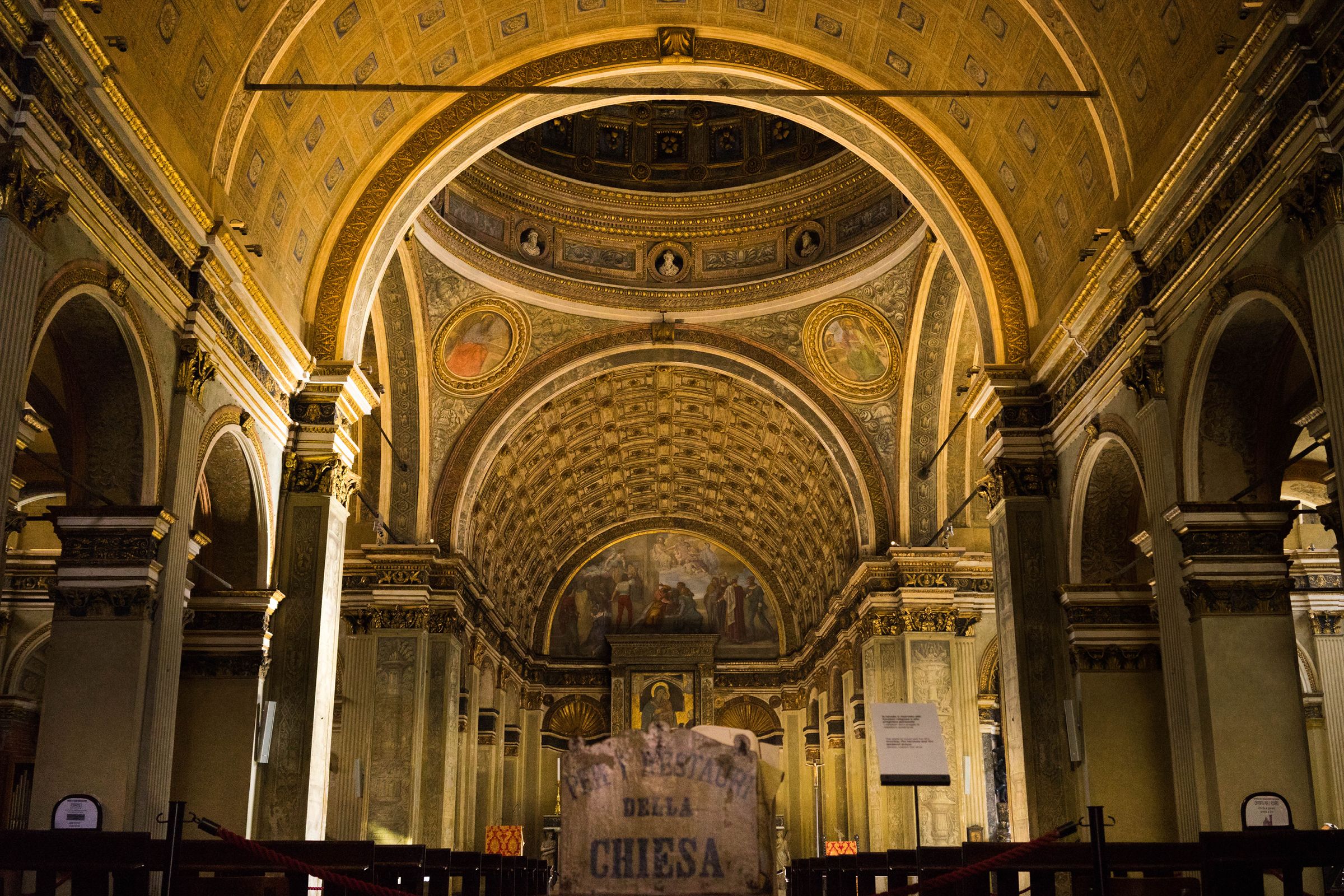 An interior with a high vaulted ceiling, arched doorways, and a central mural.