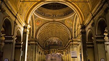 An interior with a high vaulted ceiling, arched doorways, and a central mural.
