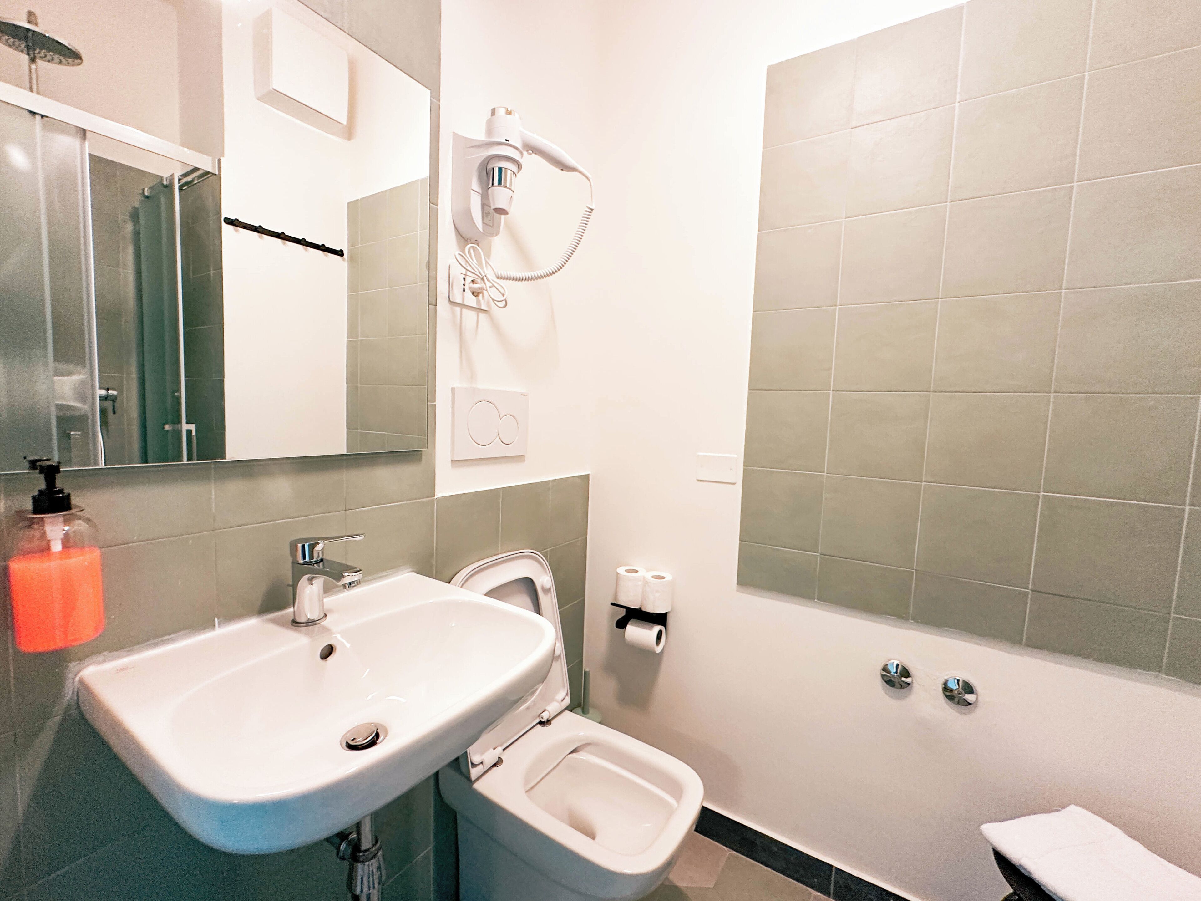 A bathroom with a sink, toilet, bidet, and a shower area.