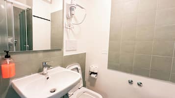 A bathroom with a sink, toilet, bidet, and a shower area.