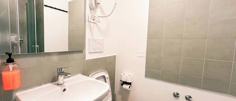 A bathroom with a sink, toilet, bidet, and a shower area.