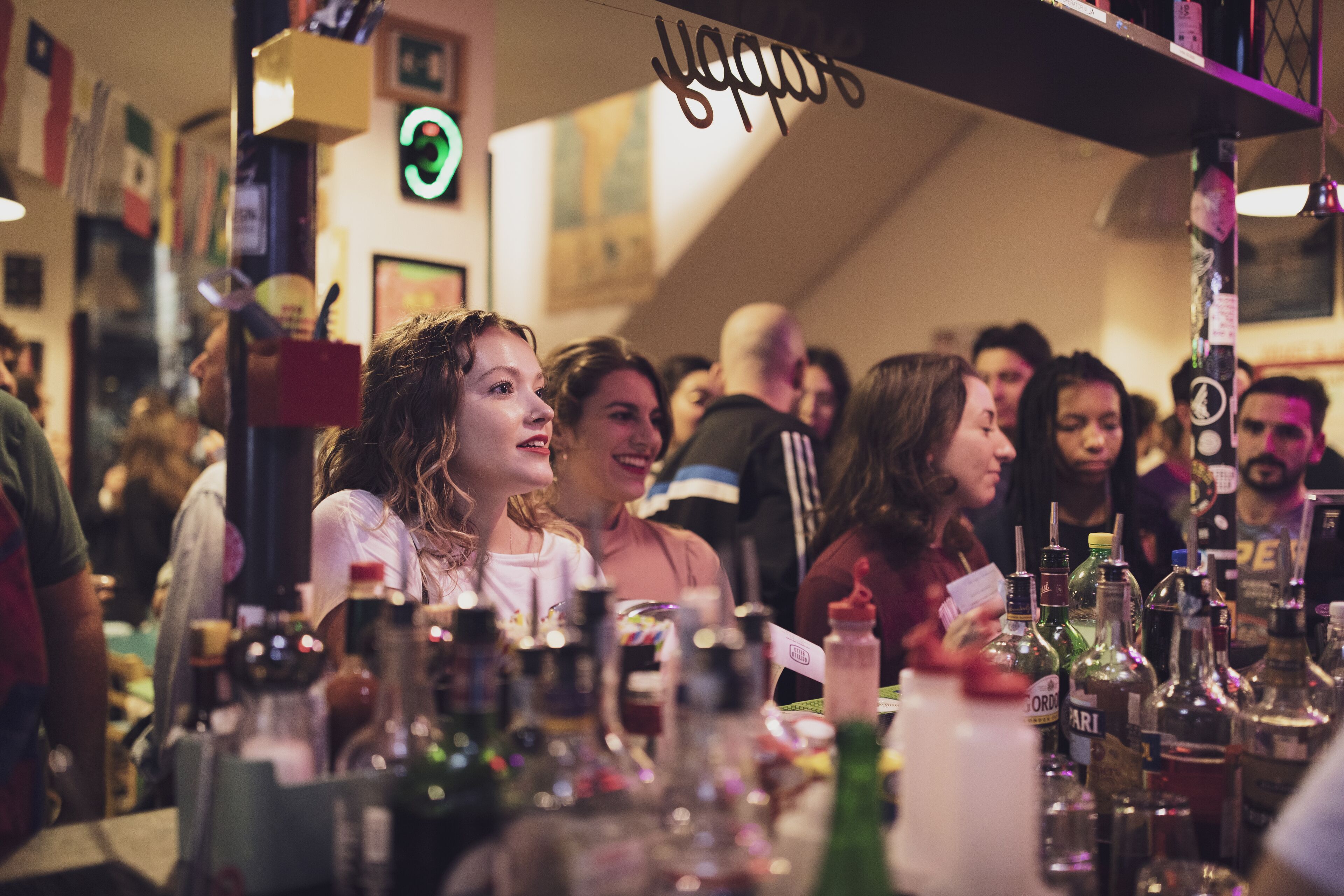 Un bar con varias botellas y un letrero de neón.
