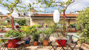 A rooftop terrace with potted plants, colorful seating, and a white paper lantern. - Ostello Bello Milano Duomo (Milan)