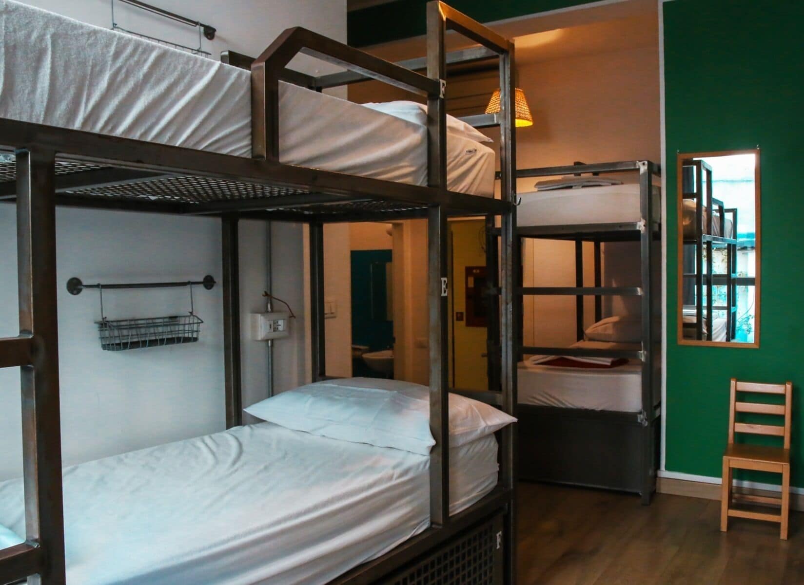 A dormitory-style room with bunk beds, a small chair, and a window with a view.