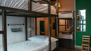 A dormitory-style room with bunk beds, a small chair, and a window with a view.