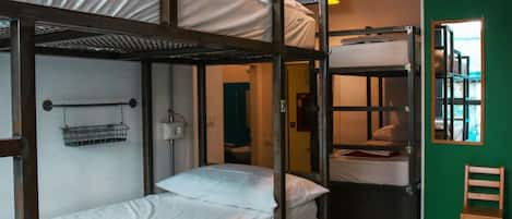 A dormitory-style room with bunk beds, a small chair, and a window with a view.