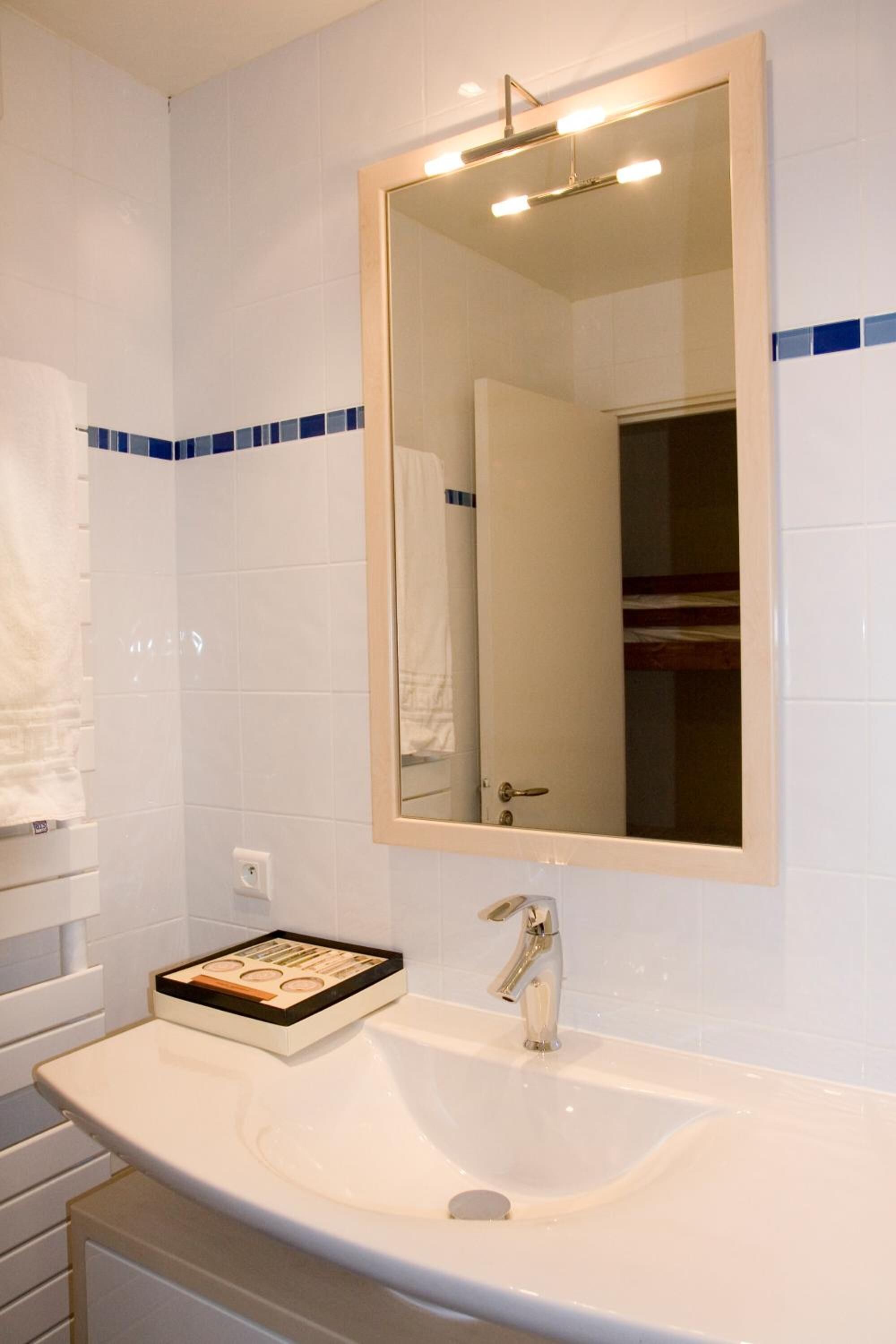 Une salle de bain avec un lavabo blanc, un miroir et un porte-serviettes.