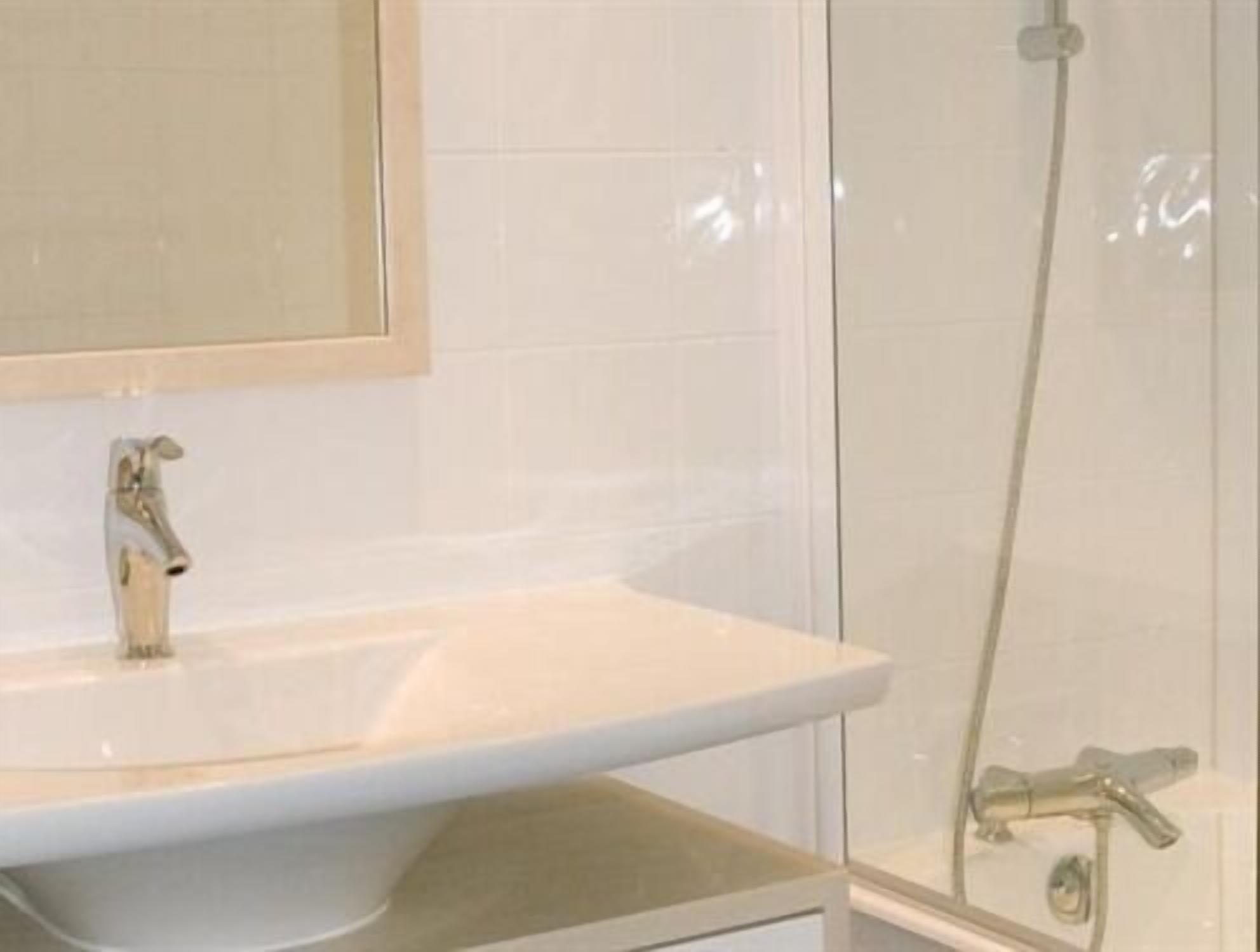 A bathroom with a white sink, a mirror, and a glass shower enclosure.