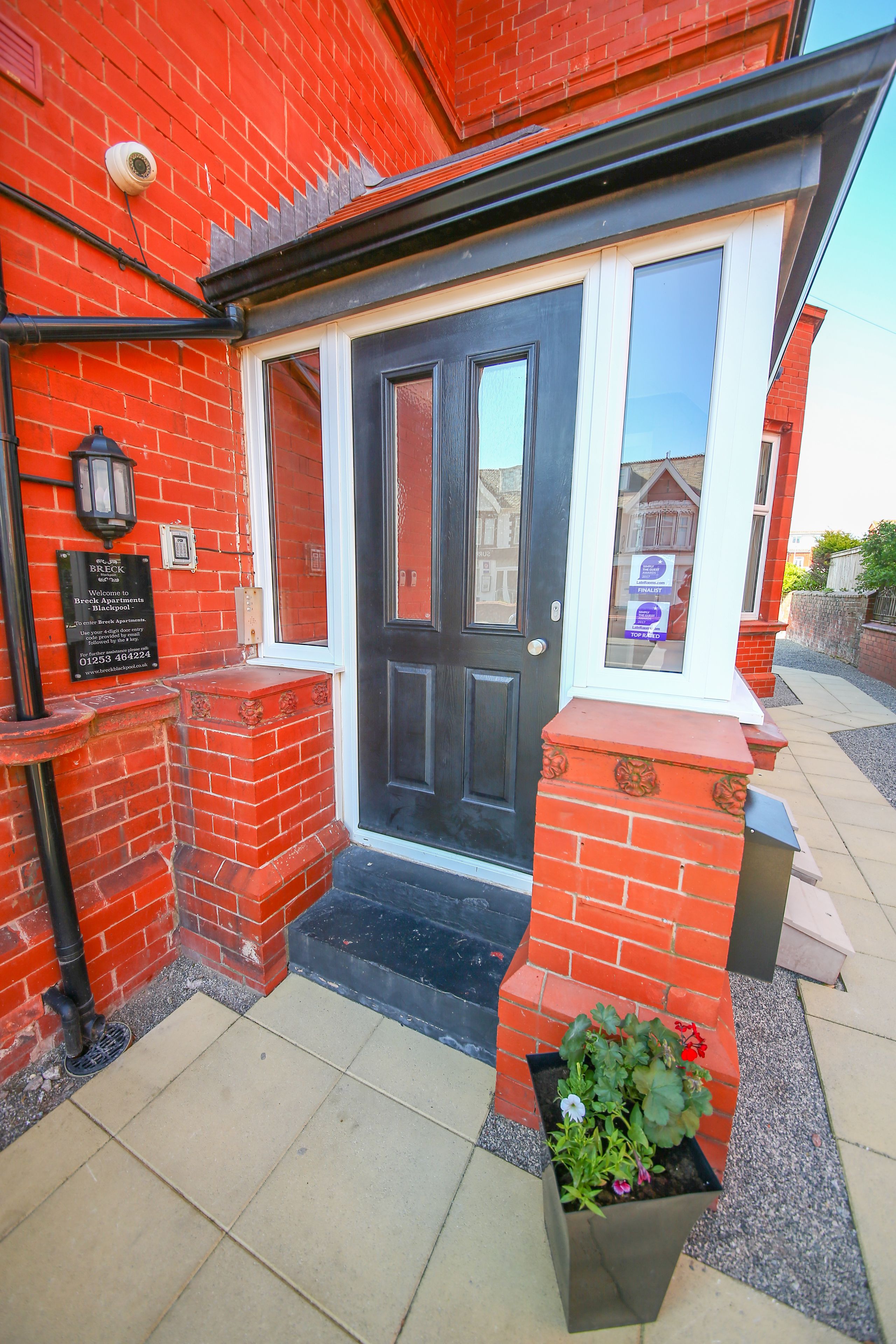 A red brick house with a black front door, a small front porch, and a mailbox.