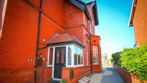 A red brick building with a small bay window entrance, a door, and a step leading to the entrance. - Breck Blackpool (Blackpool)