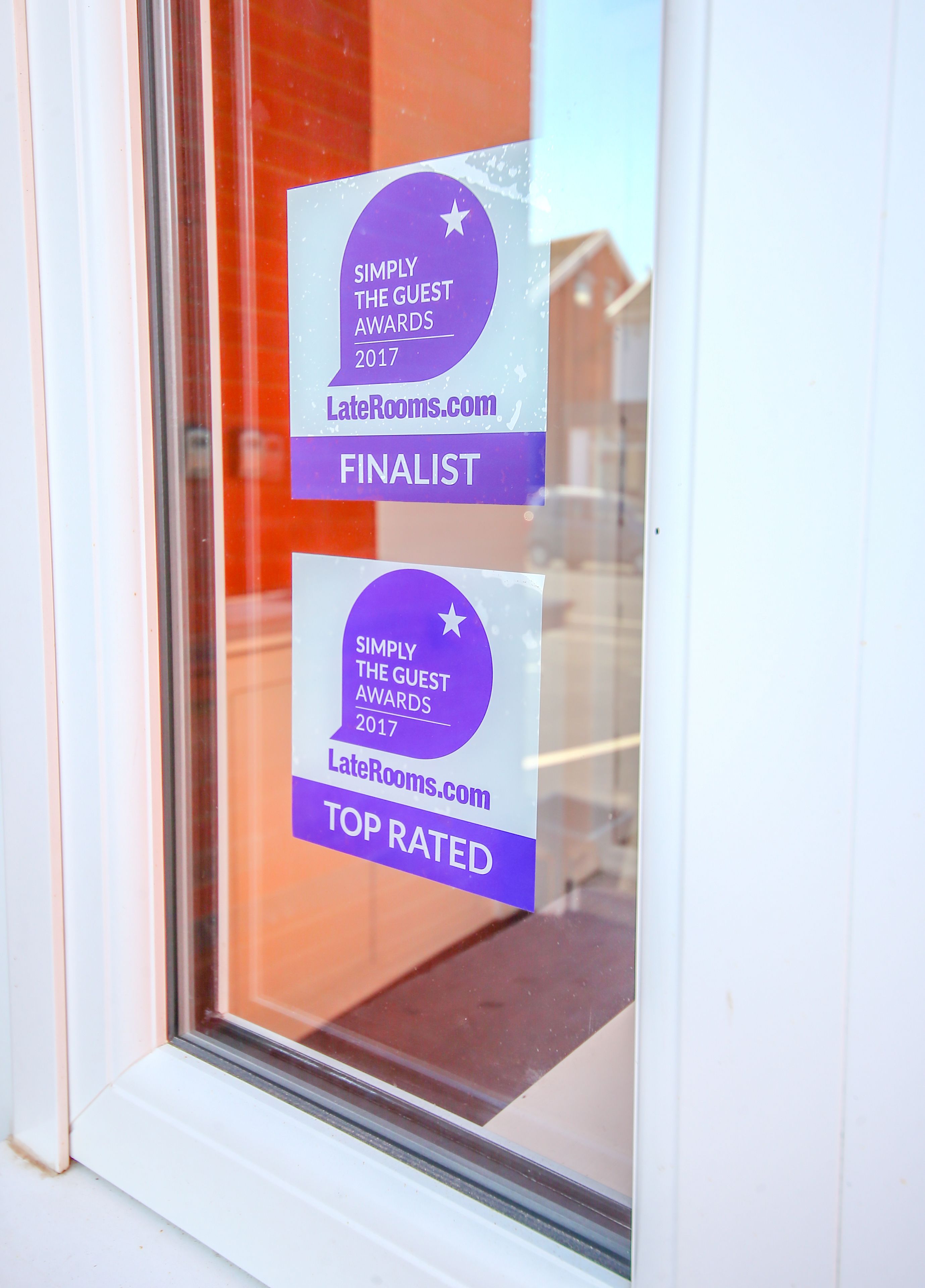 Two awards on a window, one labeled "FINALIST" and the other "TOP RATED" from Simply The Guest Awards 2017.