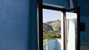 Ein Schlafzimmer mit einem Bett und einem Balkonblick, im Hintergrund ein Berg.