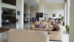 A spacious lobby with multiple seating areas, a dining area, and a kitchen visible in the background. - Taybeh Golden Hotel (Taybeh)